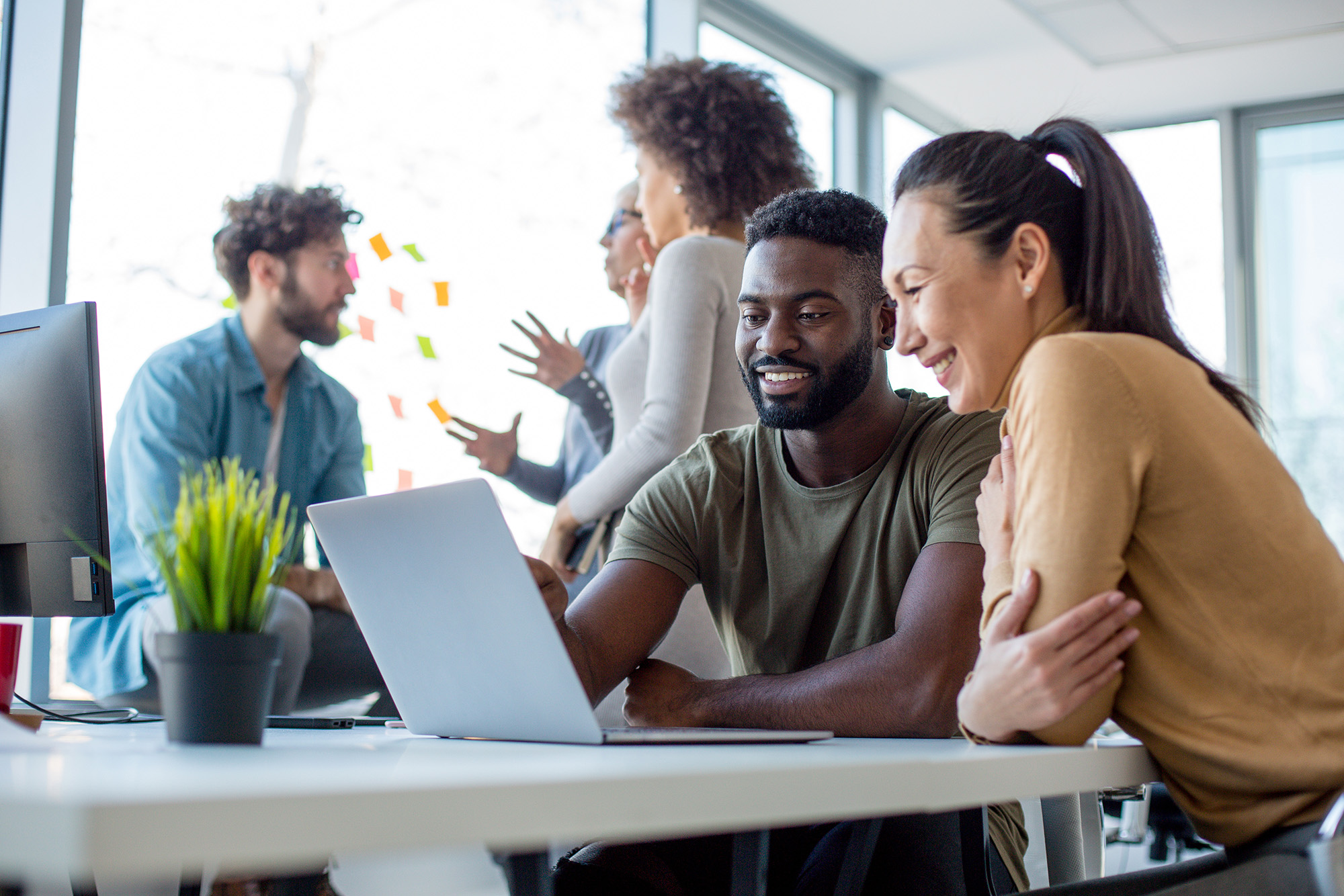 Man and woman looking at a laptop together with people in background