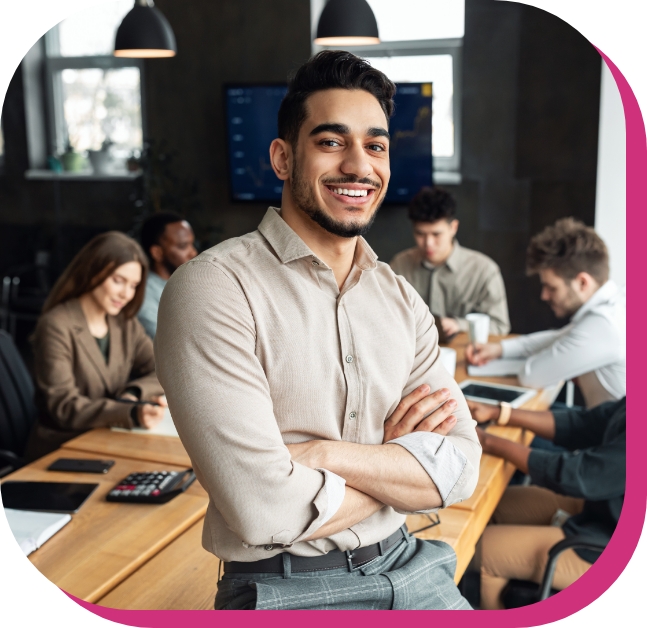 Man smiling with crossed arms in front of working colleagues