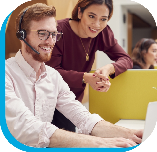 Man with headset working on computer with a woman watching