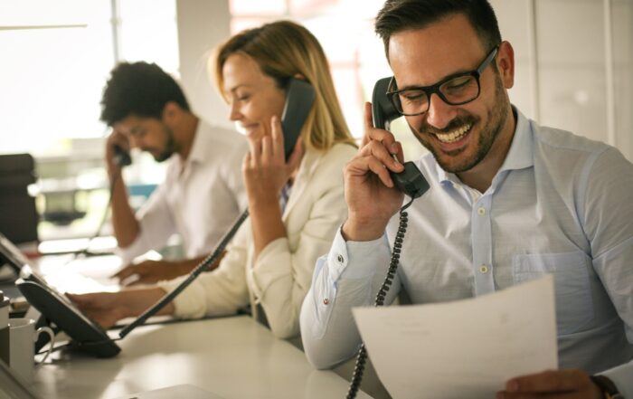 Three people talking on landlines smiling