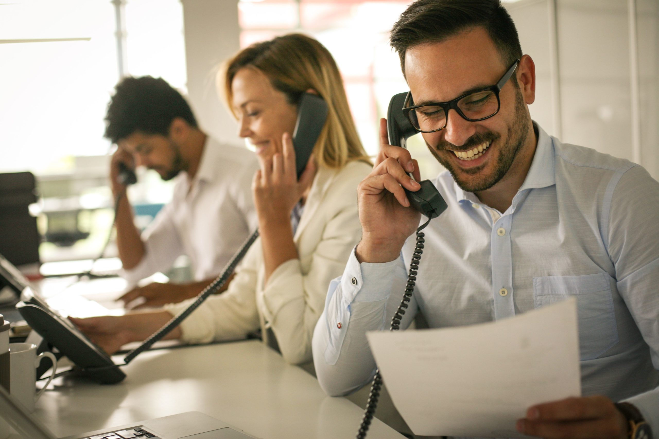 Three people talking on landlines smiling