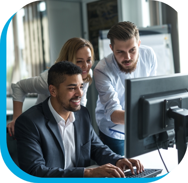 Man working on a computer with colleagues over his shoulder