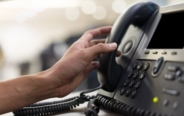 Hand picking up a call from a landline telephone