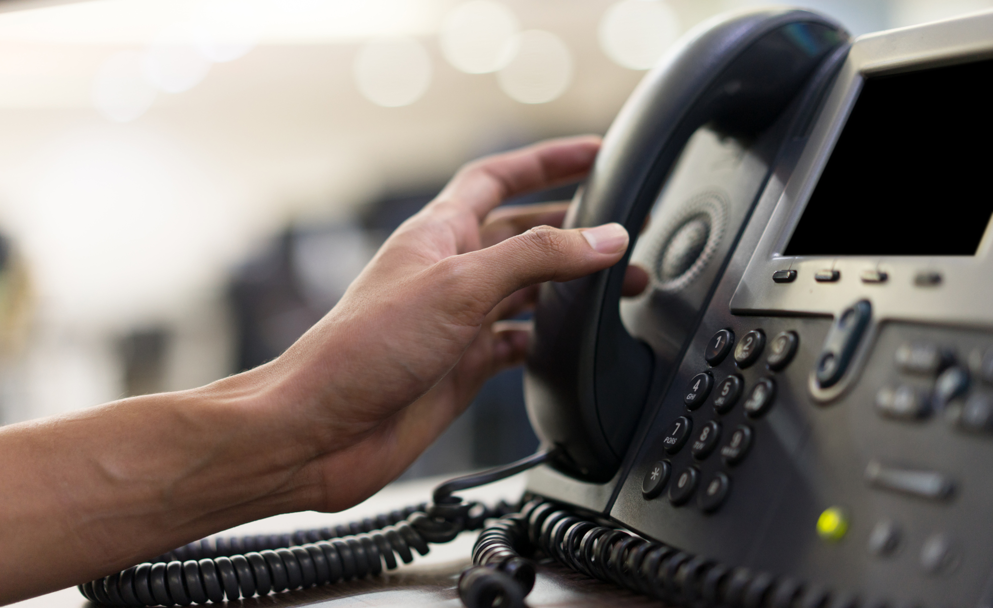 Hand picking up a call from a landline telephone